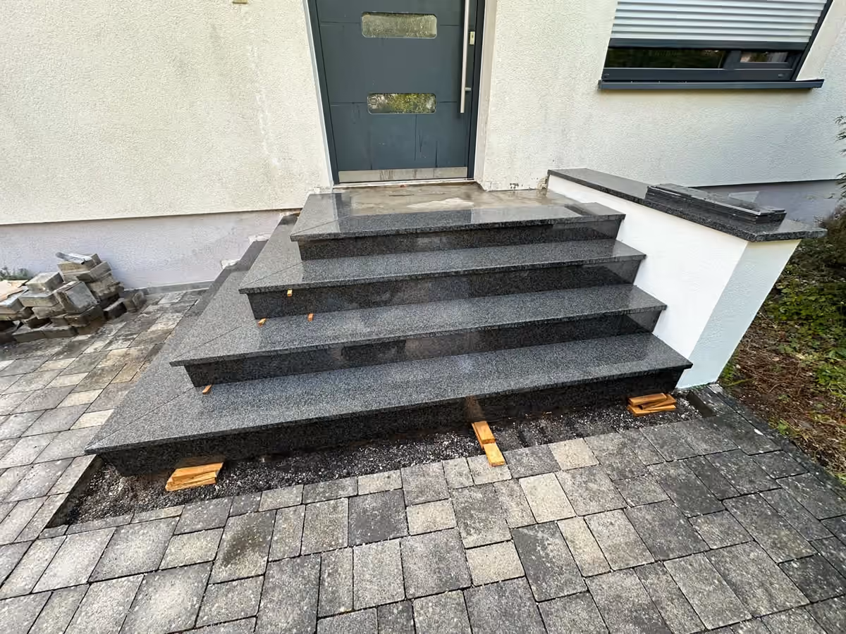 Neu aufgebaute Eingangstreppe mit dunklen Granitstufen nach der Treppensanierung