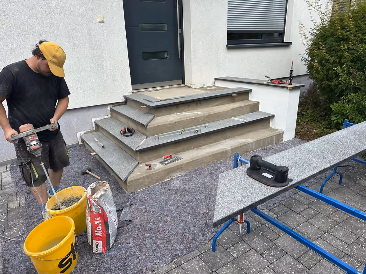 RenoTec Mitarbeiter beim Verlegen der neuen Granitstufen auf der Eingangstreppe